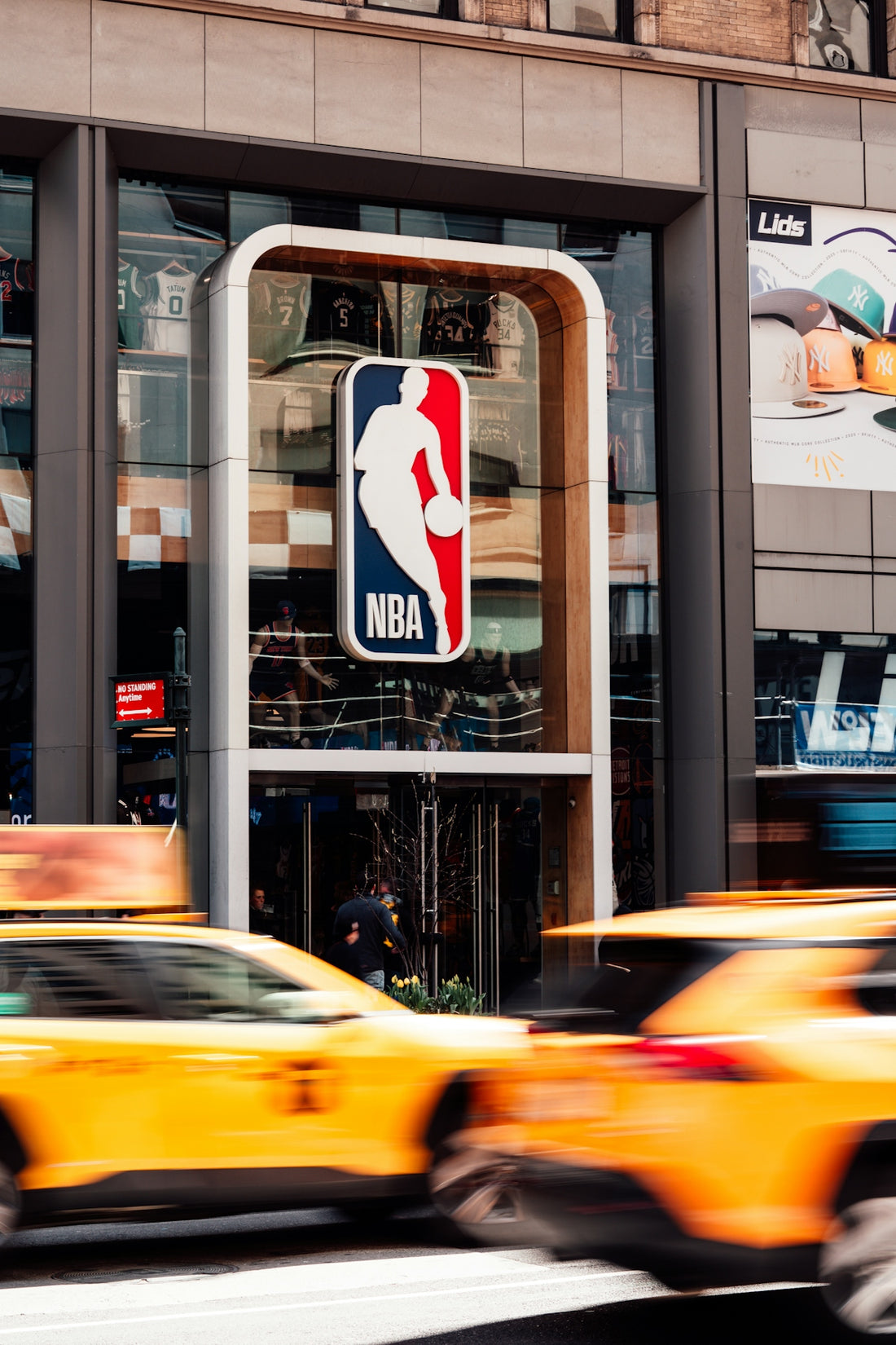 NBA store sign with yellow cabs driving past.